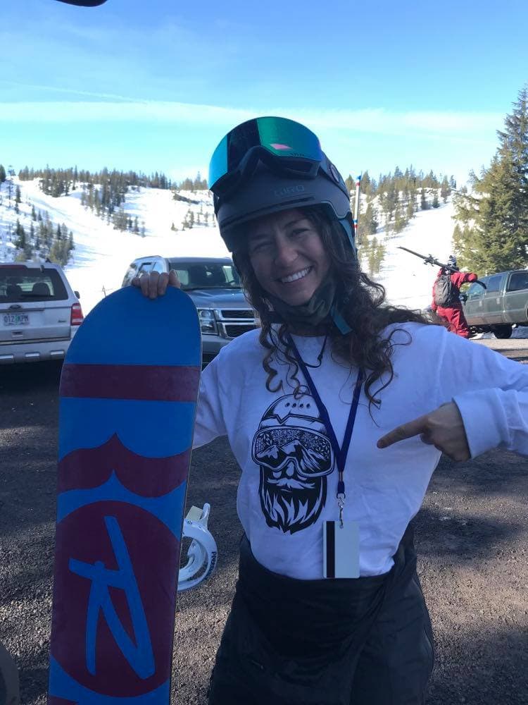 Francesca Jacquez smiling on a snowy mountainside with her splitboard, backcountry terrain in the background.
